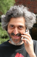 Mężczyzna w siwych włosach i brodzie rozmawiający przez telefon.
