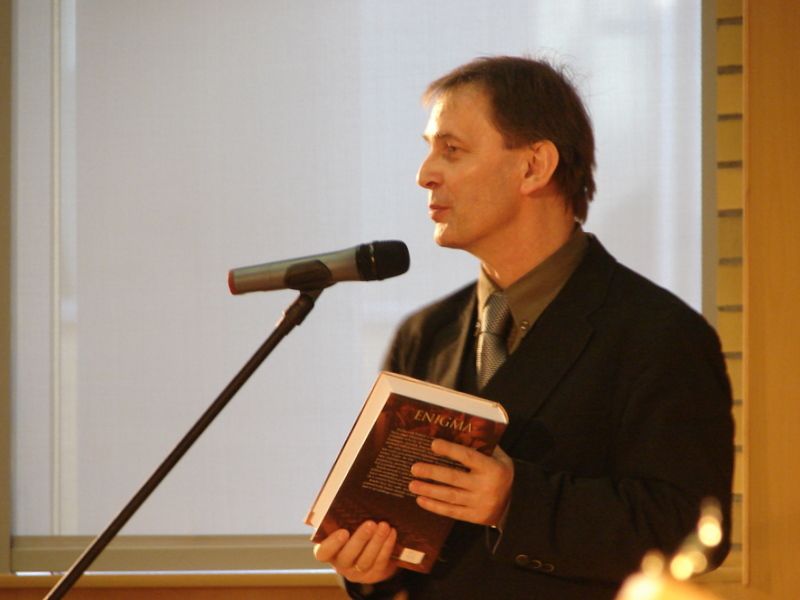 Mężczyzna z książką w ręce przy mikrofonie.