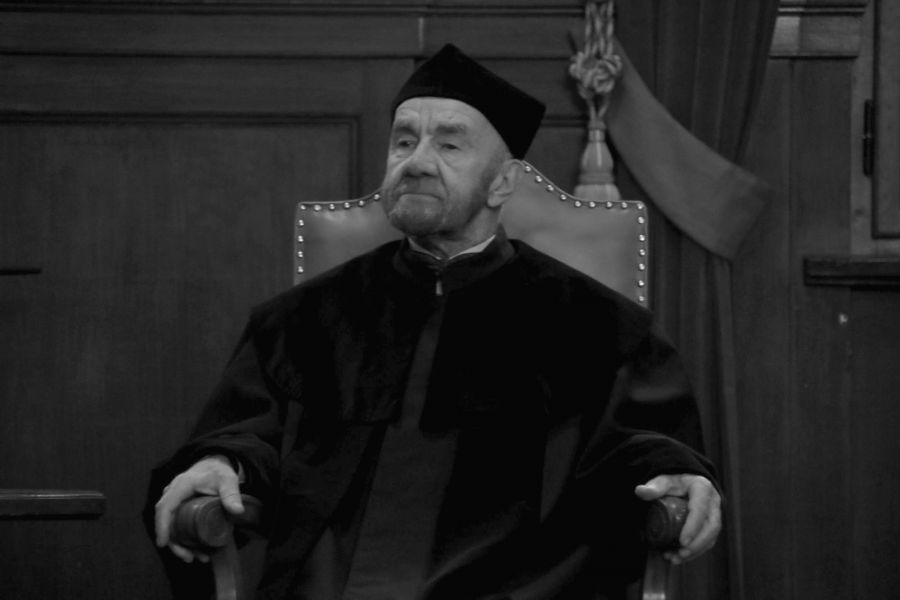 Czarno białe zdjęcie profesora Drewnowskiego siedzącego w fotelu podczas uroczystości odnowienia doktoratu