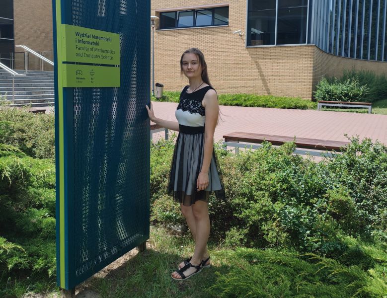 Zdjęcie pani Natalii Adamskiej stojącej przed tablicą Wydział Matematyki i Informatyki UAM